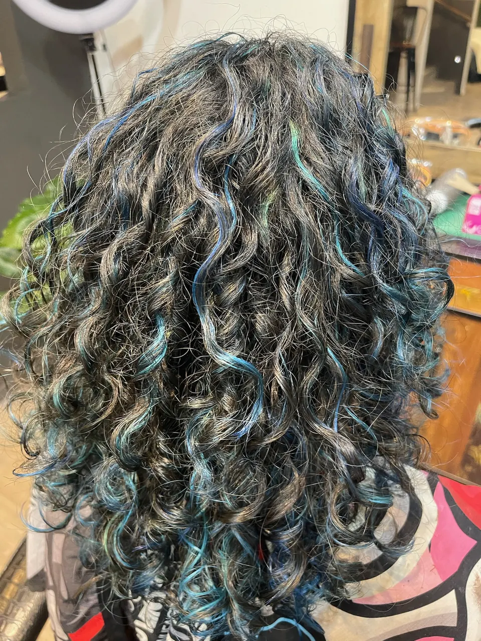 Blue and teal ribbons running through defined natural curls.