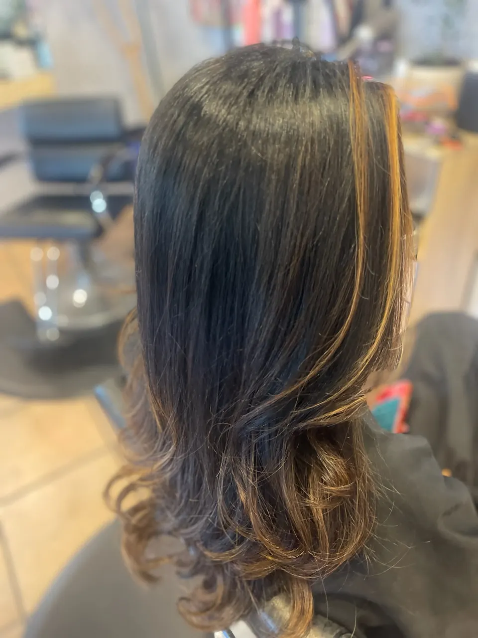 Dark hair broken up with fine caramel ribbons and curled ends.
